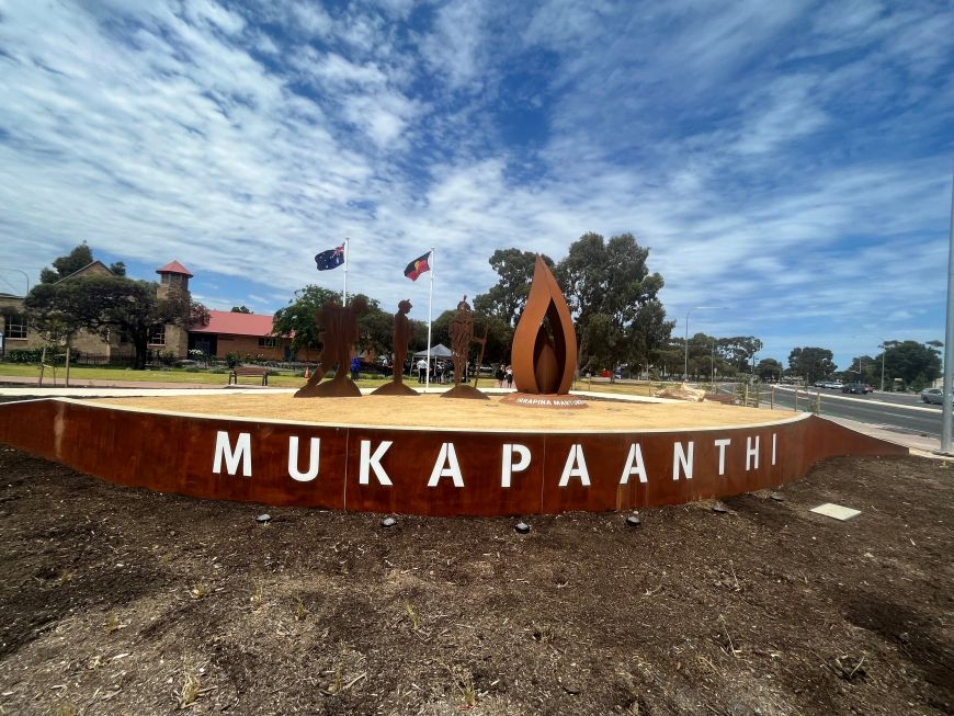 The Mukapaanthi installation, the metal artwork features a ceremonial flame and three figures.